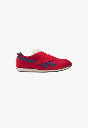 Zapatilla deportiva roja de perfil bajo con rayas azules en los costados, cordones rojos, suela blanca y una lengüeta para tirar en el talón, vista desde el lado exterior.