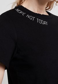 Black cotton t-shirt featuring a crew neck and short sleeves. "NOPE NOT TODAY" embroidered in white at the neckline. Smooth texture.