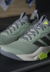 Baskets de sport vertes avec une tige en maille et en caoutchouc, motifs texturés, accents gris et languette au talon vert lime. Les lacets sont fixés pour un maintien optimal.