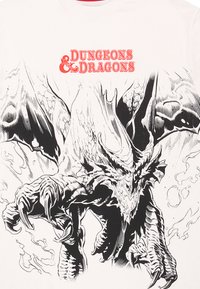 Bílý tričko s ilustrací černého a šedého draka s drápy a křídly, na kterém je umístěný červený text "Dungeons & Dragons."