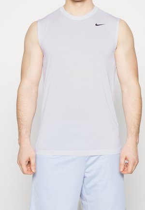 Mann trägt hellgraues ärmelloses Nike-Sportshirt und hellblaue Shorts, steht mit entspannten Armen an den Seiten.