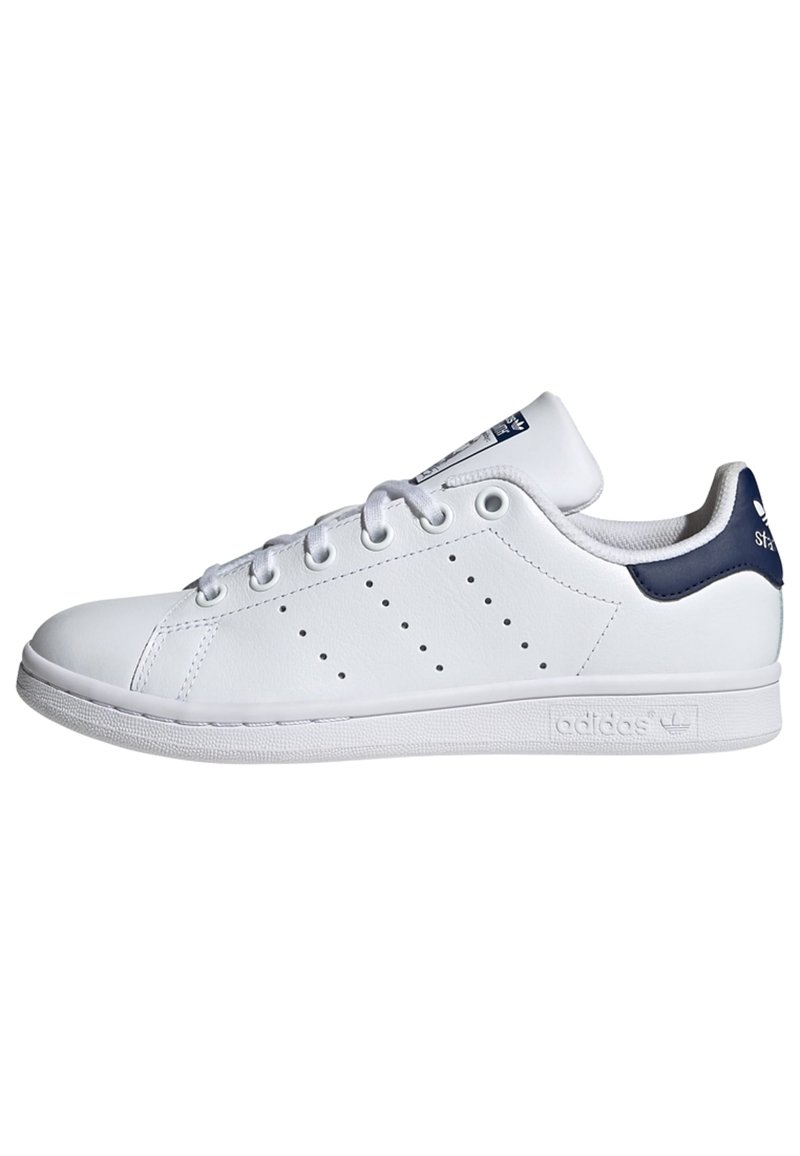 White leather sneaker with navy heel and tongue accents, round toe, perforated side design, and white rubber sole with branding detail.