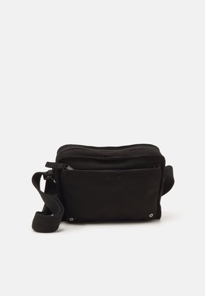Petit sac bandoulière en tissu noir avec compartiment principal zippé, poche avant, sangle réglable et logo Levi's discret.