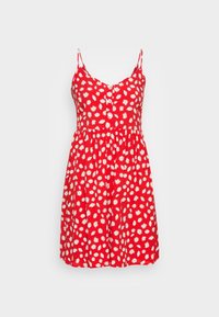 Röd ärmlös sommardress med vit tusenskjöna-blommig mönster, knappad front och tunna axelband på ljusgrå bakgrund.