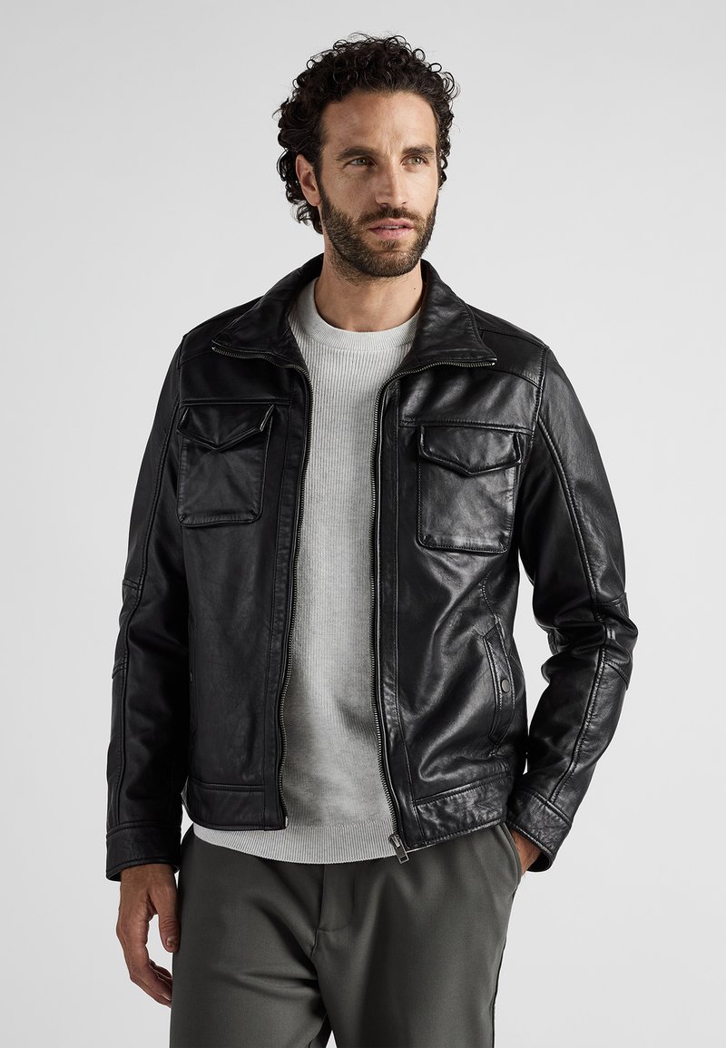 Zwarte leren jas met een ritssluiting aan de voorkant, puntige kraag en vier zakken. Het ontwerp heeft een gladde textuur en een getailleerde pasvorm.