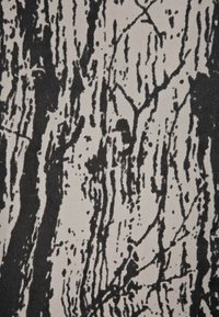 Tejido texturizado en beige con un patrón de corteza de árbol negro, que presenta líneas verticales y formas irregulares, creando un diseño inspirado en la naturaleza.