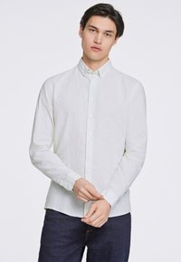 Ljusgrön linne långärmad skjorta med button-down-krage och enkelknappade ärmar, med en texturerad yta och rak fåll.