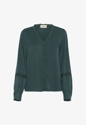 Grön långärmad blus, gjord av slät tyg. Har en V-hals, dekorativ kant, knäppning fram och spetsdetaljer vid ärmarna.