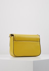 Žlutá kožená crossbody taška s texturovaným povrchem, jednoduchý design, akcenty na bočních švech a stříbrnými detaily.