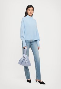 Gaiši zils ribots adīts turtlenecks, apvienots ar gaišas krāsas taisnām biksēm un mezgla stila lavandas krāsas rokassomu. Melni zābaki ar sašaurinātu purngalu.