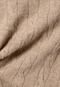 Beige Kabelstrickstoff mit weichem Gefühl, der erhabene, verdrehte Muster zeigt. Das Material wirkt warm und gemütlich.