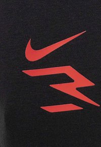 Tessuto nero con un prominente logo rosso di Nike, caratterizzato da forme dinamiche che evidenziano una texture liscia e elementi di design atletico.