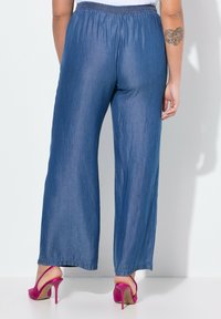 Dżinsowe spodnie szerokie z elastycznym pasem, w jasnoniebieskim kolorze i gładkiej strukturze. W połączeniu z różowymi szpilkami.