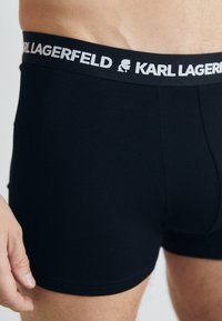Zwarte boxershorts van rekbaar stof, met een contrasterende witte tailleband voorzien van de tekst "KARL LAGERFELD" en een logo.