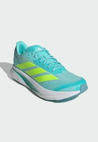 Light blue athletic shoe with mesh fabric, white sole, and bright green accent stripes. Features a padded collar and flat laces.