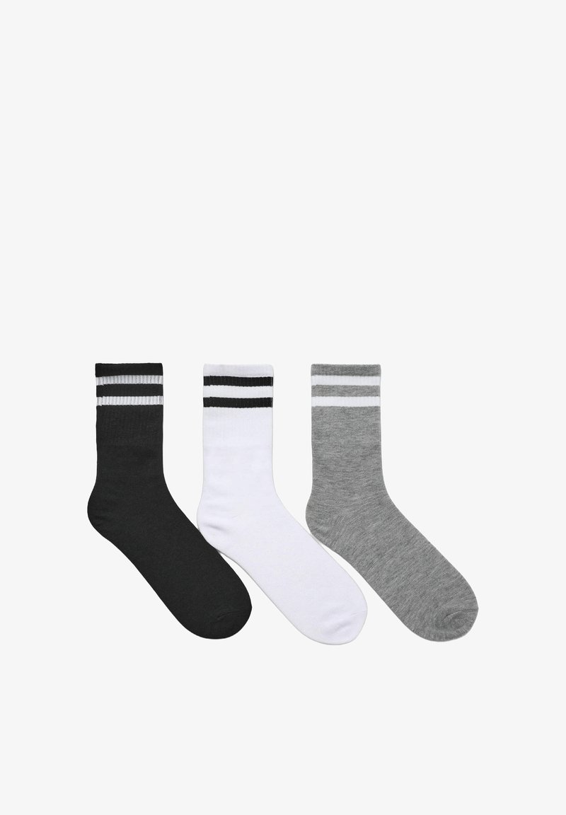 Tre paia di calze: una nera con righe bianche, una bianca con righe nere e una grigia. Tutte sono di lunghezza crew e con una texture liscia.