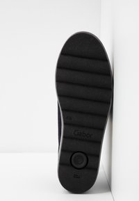 Semelle de chaussure noire avec des rainures horizontales, nom de la marque Gabor, taille 4½, et texte Made in Slovenia visible.
