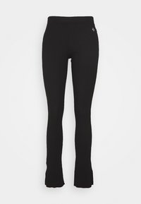 Svart utsvängda leggings i elastiskt tyg. Har ett hög midja och en diskret logotypdetalj på höften. Slät textur genomgående.
