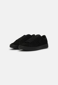 Zapatillas negras de ante, con un diseño de perfil bajo, cierre de cordones y una suela de goma suave con acentos texturizados.