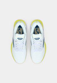 Λευκά αθλητικά παπούτσια με υφή στο επάνω μέρος, μπλε λεπτομέρειες και φωτεινή κίτρινη σόλα. Τα κορδόνια είναι κανονικά με μαλακή εσωτερική επένδυση.