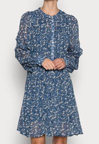 Blaues Blumenkleid mit langen Ärmeln, Knopfleiste, gefalteter Taille und ausgestelltem Rock, aus leichtem, durchscheinendem Stoff.