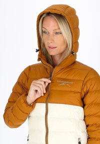 Puchowa kurtka w kolorze pomarańczowym i białym, z zapięciem na zamek, regulowanym kapturem i logo na piersi. Gładka faktura z przeszytymi panelami.