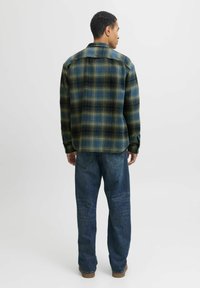 Grün- und blaues karierte Flanellhemd mit einem lässigen Schnitt, Button-Down-Kragen und langen Ärmeln, kombiniert mit dunkelblauen Jeans.