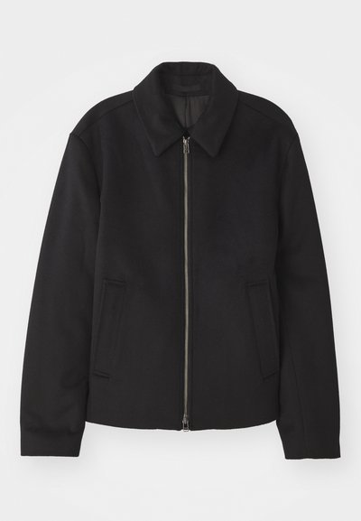 Black jacket with a zip closure, tailored design, a rounded collar, and slit pockets. Made from a smooth, textured fabric.