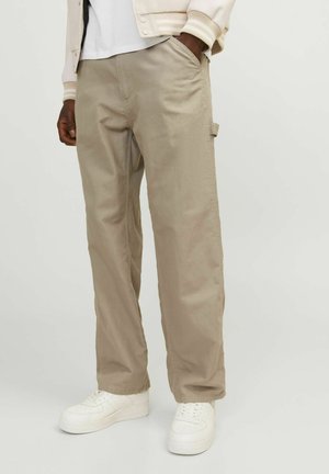 Beige cargo pants with side pocket detail, made from soft fabric, featuring a relaxed fit and stitched accents, paired with white sneakers.