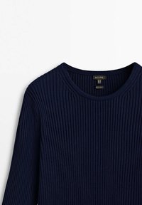 Pull en tricot côtelé bleu marine avec un col rond et des manches longues, montrant la partie supérieure avant et le col.