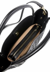 Sac à main en cuir noir avec un extérieur texturé et une doublure beige lisse. Comprend une poche zippée et des accents en métal doré.
