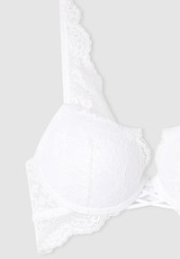 Reggiseno in pizzo bianco con coppe imbottite, bordi ondulati e dettagli incrociati sulle spalle sul retro, realizzato in un tessuto morbido e texturizzato.