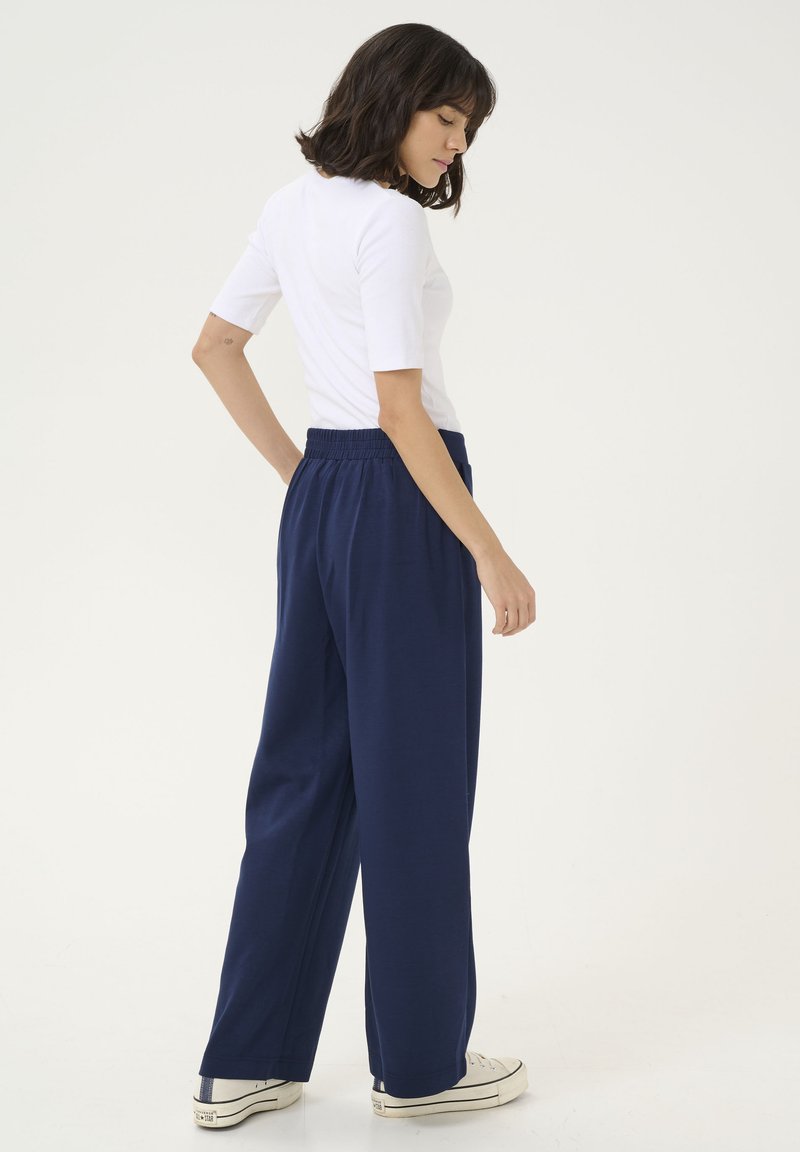 Marineblauwe wijde broek met een elastische tailleband, gecombineerd met een aansluitend wit topje. Eenvoudig ontwerp en zachte stofstructuur. Casual schoeisel.