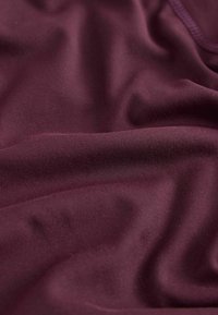 Tissu violet profond, lisse, avec des plis doux et une texture subtile, montrant un drapé naturel et des ombres délicates.