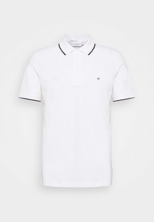 White polo shirt made of cotton, featuring a collared neckline, three buttons, and black accents on the collar and sleeves. Small logo on chest.
