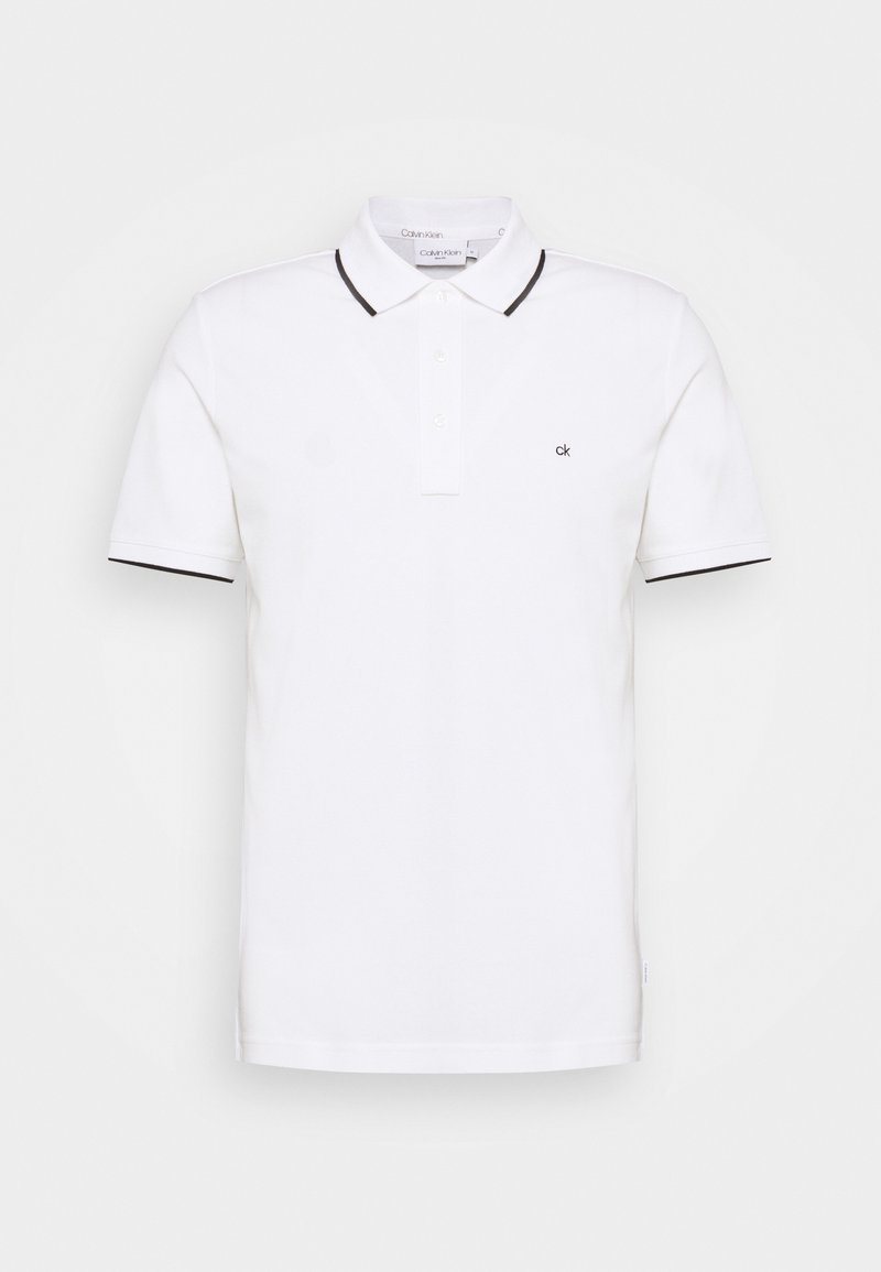 Polo shirt blanc en coton, avec un col, trois boutons et des accents noirs sur le col et les manches. Petit logo sur la poitrine.