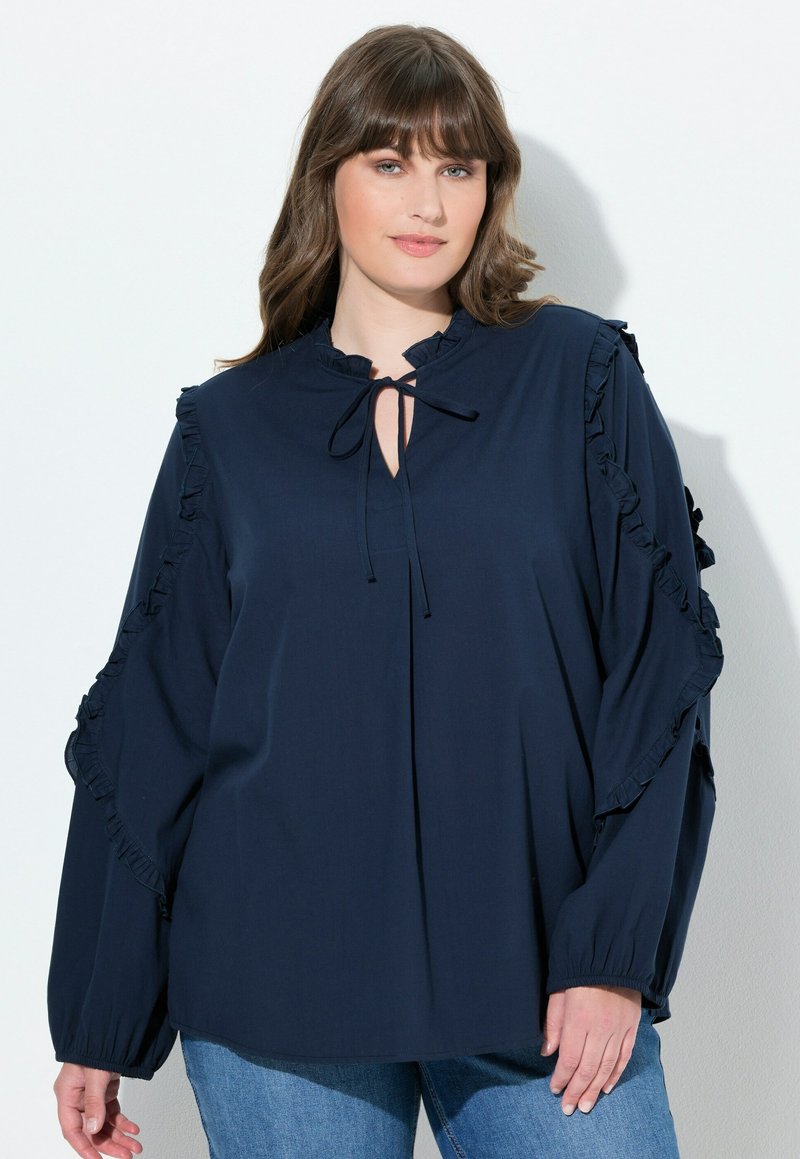 Marineblaue Bluse aus weichem Stoff mit Rüschendetails an den Ärmeln und einem Schlüsselloch-Ausschnitt. Lange Ärmel mit gerafften Manschetten.
