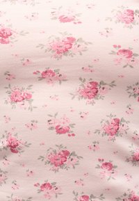 Απαλό ροζ ύφασμα με διάσπαρτες συστάδες μικρών κόκκινων και ροζ τριαντάφυλλων και πράσινων φύλλων σε ένα λεπτεπίλεπτο λουλουδάτο σχέδιο.