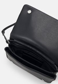Svart läderhandväska med en strukturerad design. Har ett magnetiskt snapslås och flera inre fack för organisering.