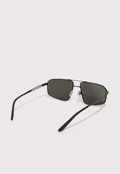 Μαύρα ορθογώνια γυαλιά ηλίου με λεπτά μεταλλικά πλαίσια και σκούρους φακούς σε λευκό φόντο.