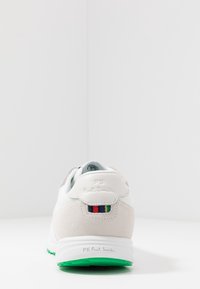 Weiße und hellgraue Sneaker mit Akzenten aus Wildleder, grüner Sohle und mehrfarbigen Streifen auf der Ferse, geprägt mit Logo auf der Rückseite.