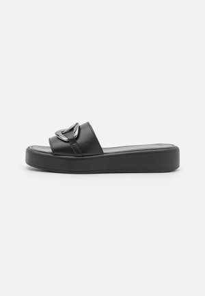 Schwarze Slide-Sandalen mit einer dicken, strukturierten Plattformsohle. Der Riemen hat eine glänzende silberne Akzentuierung und eine glatte Lederoberfläche.