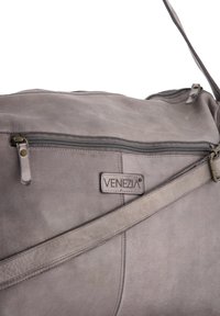 Szara skórzana torba z zamkiem błyskawicznym, logo VENEZIA, regulowanym paskiem i gładką teksturą z subtelnymi detalami przeszycia.