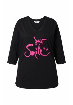 Zwarte V-hals T-shirt met 3/4 mouwen, versierd met gedurfde roze tekst "just Smile" en kleine hartaccenten, gemaakt van zachte katoen stof.