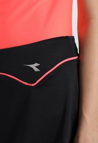 Svarta idrottsshorts med en rosa accent längs fållen och fickan. Har en logotyp på sidan, tillverkad av lätt och stretchigt material.