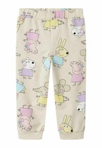 Helle beige joggebukser med fargerike tegneseriefigurer. Elastisk midjebånd og nedbrettede hem. Myk stoff med lekne mønstre.
