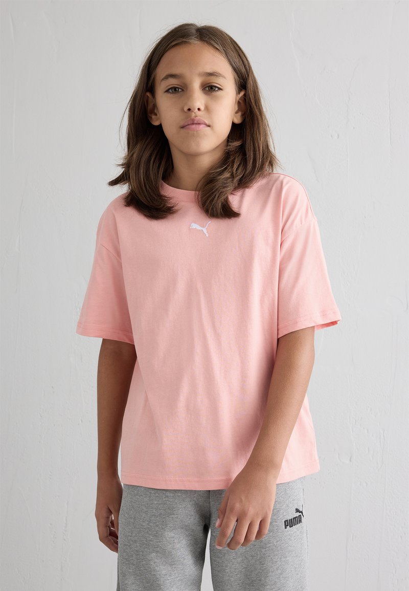 Ροζ βαμβακερό μπλουζάκι με κοντό μανίκι και στρογγυλή λαιμόκοψη. Διαθέτει ένα μικρό λευκό λογότυπο Puma μπροστά. Συνδυάζεται με γκρί φόρμες.