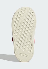 Sole bijele Adidas tenisice s uzorkom u obliku saća i Adidas logotipom, prikazana na svijetloj pozadini.
