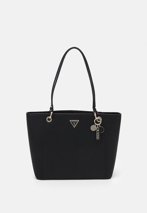 Sort Guess tote taske med dobbelte håndtag, trekantet logo-plade og tre sølv dekorative charms foran.
