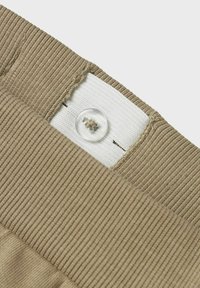 Khakifarbener Stoffbund mit gerippter Textur, ausgestattet mit einem klaren Knopf und einem weißen Stoffetikett mit Nähten und einem Nadelstich-Detail.